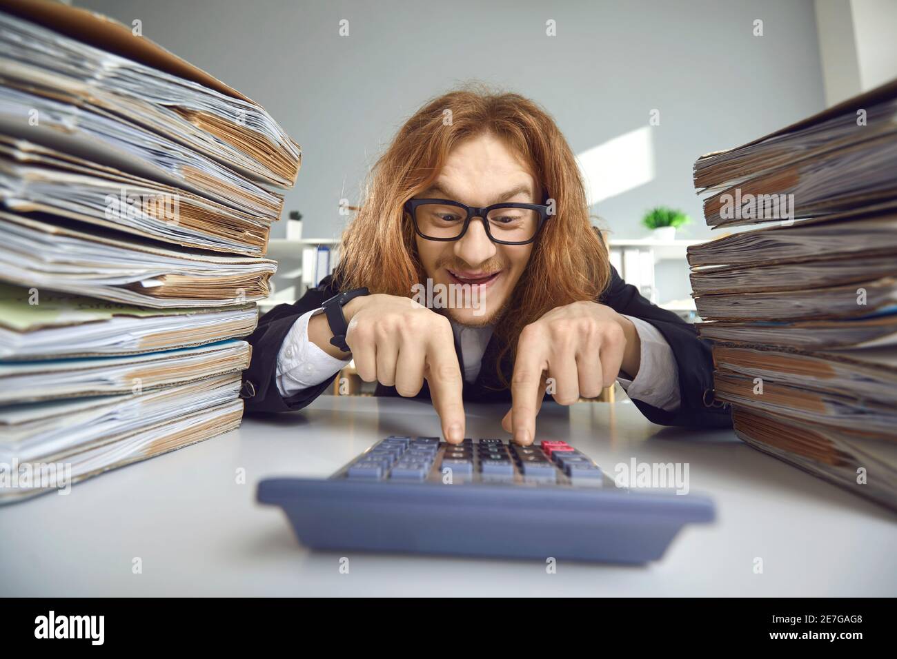 Lustige Buchhalter sitzen am Schreibtisch mit Rechner und Berechnung Steuerbetrag Stockfoto