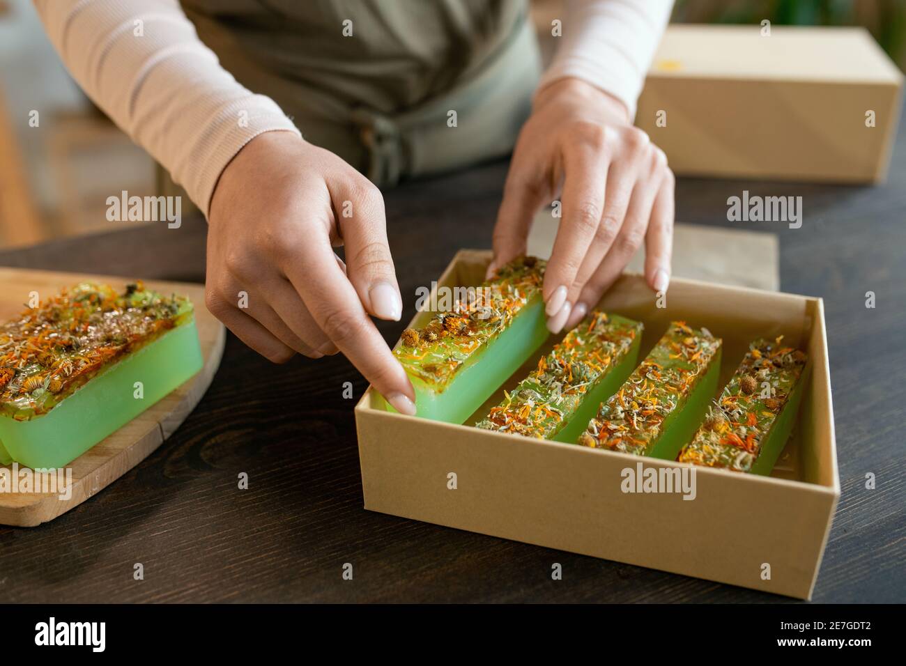 Hände der jungen Frau Verpackung Bars von frischen handgefertigten natürlichen Seife in Karton geschenkbox während der Vorbereitung Geschenke für ihre Freunde Vor dem Urlaub Stockfoto