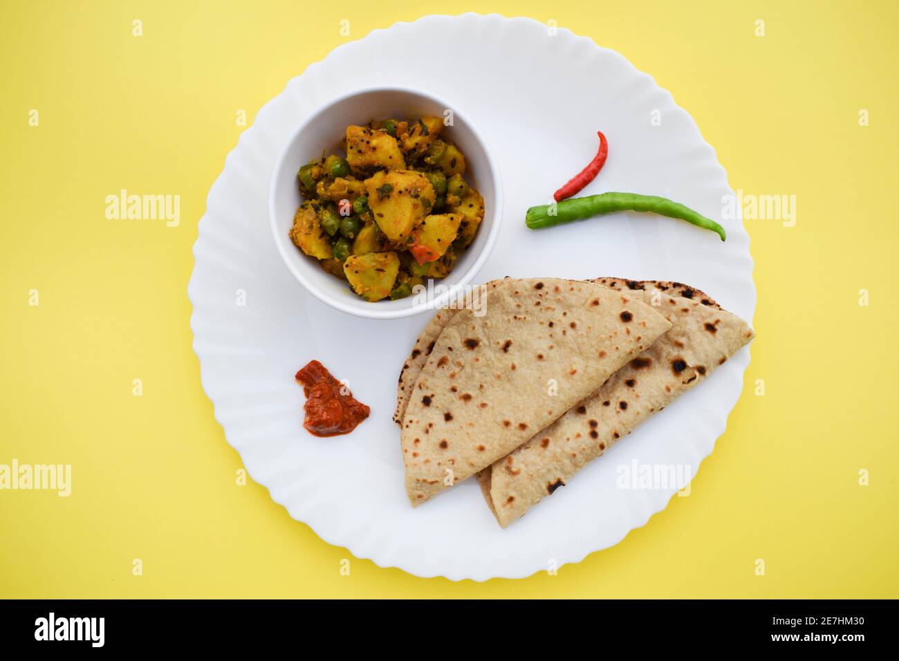 Selektiver Fokus der indischen Beilage Curry Aloo mattar KI Sabzi, beliebtes Curry aus Kartoffeln und grünen Erbsen mit Rotis serviert Stockfoto