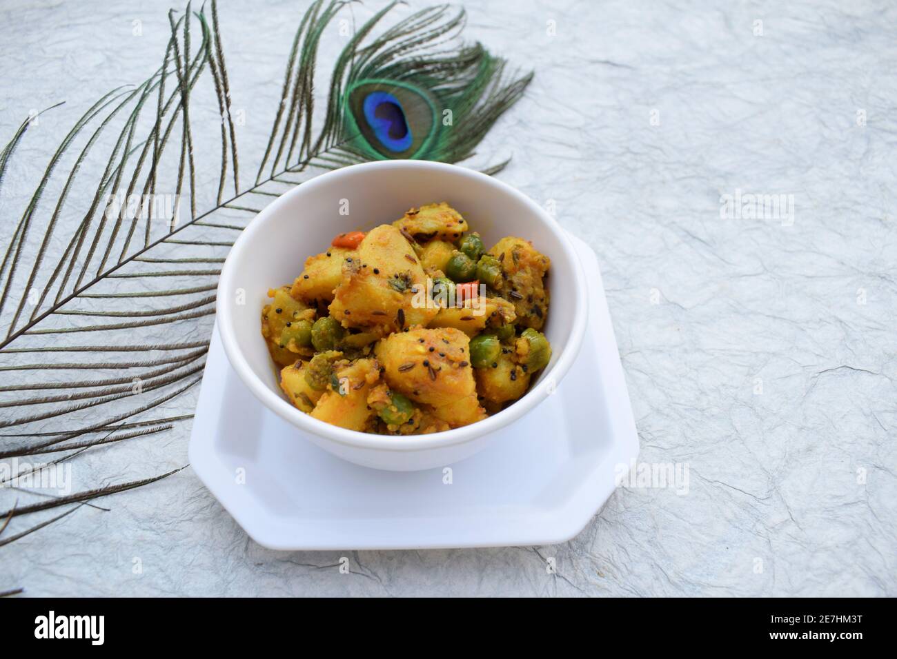 Selektiver Fokus der indischen Beilage Curry Aloo mattar KI Sabzi, beliebtes Curry aus Kartoffeln und grünen Erbsen auf weißem Hintergrund Stockfoto