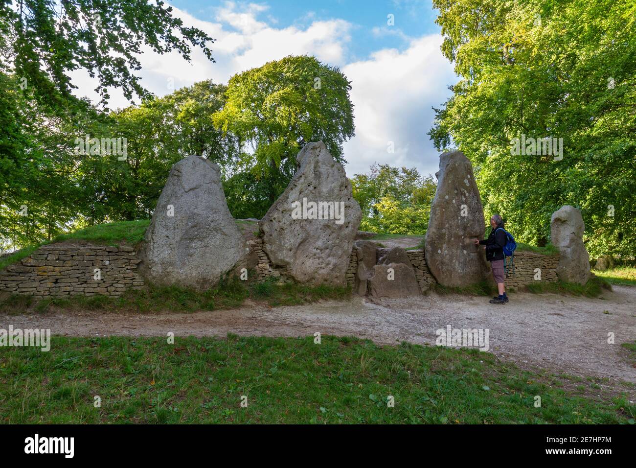 Mann, der vor den Eingangssteinen zu Wayland's Smithy a Neolithisches Grab auf den Downs oberhalb des Vale of the White Horse, Oxfordshire, Großbritannien, steht. Stockfoto