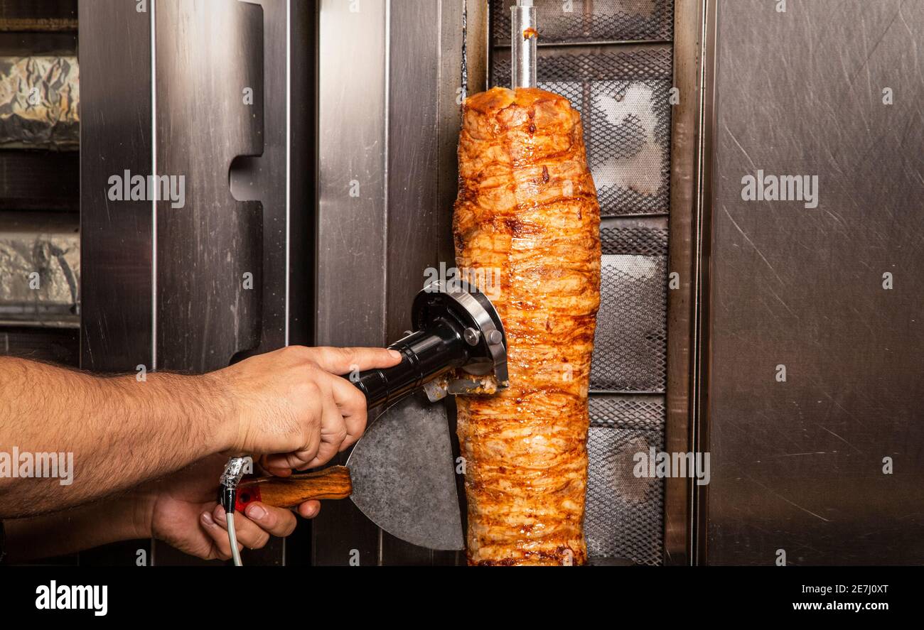 Nahaufnahme von Kebab und eine Hand schneidet das Fleisch mit Slicer Stockfoto