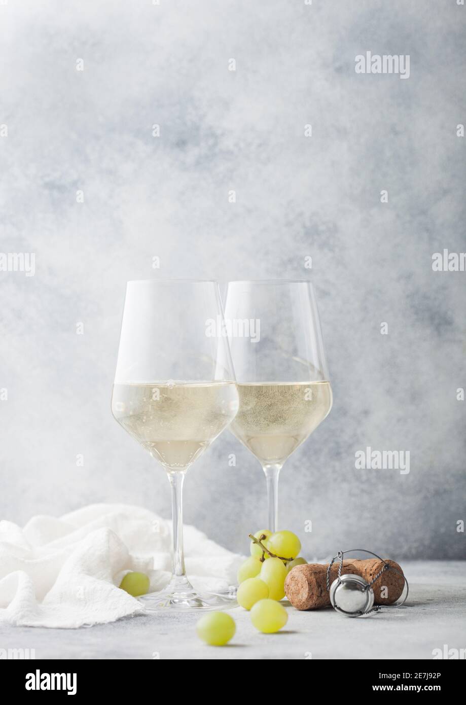 Gläser von weißen hausgemachten Sommer erfrischenden Wein mit Korken und Trauben auf hellem Stein Hintergrund. Stockfoto