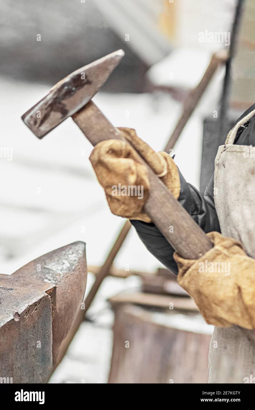 Der Junge, der Sohn des Schmieds, steht am Amboss. Der Prozess des Schmiedens. Stockfoto