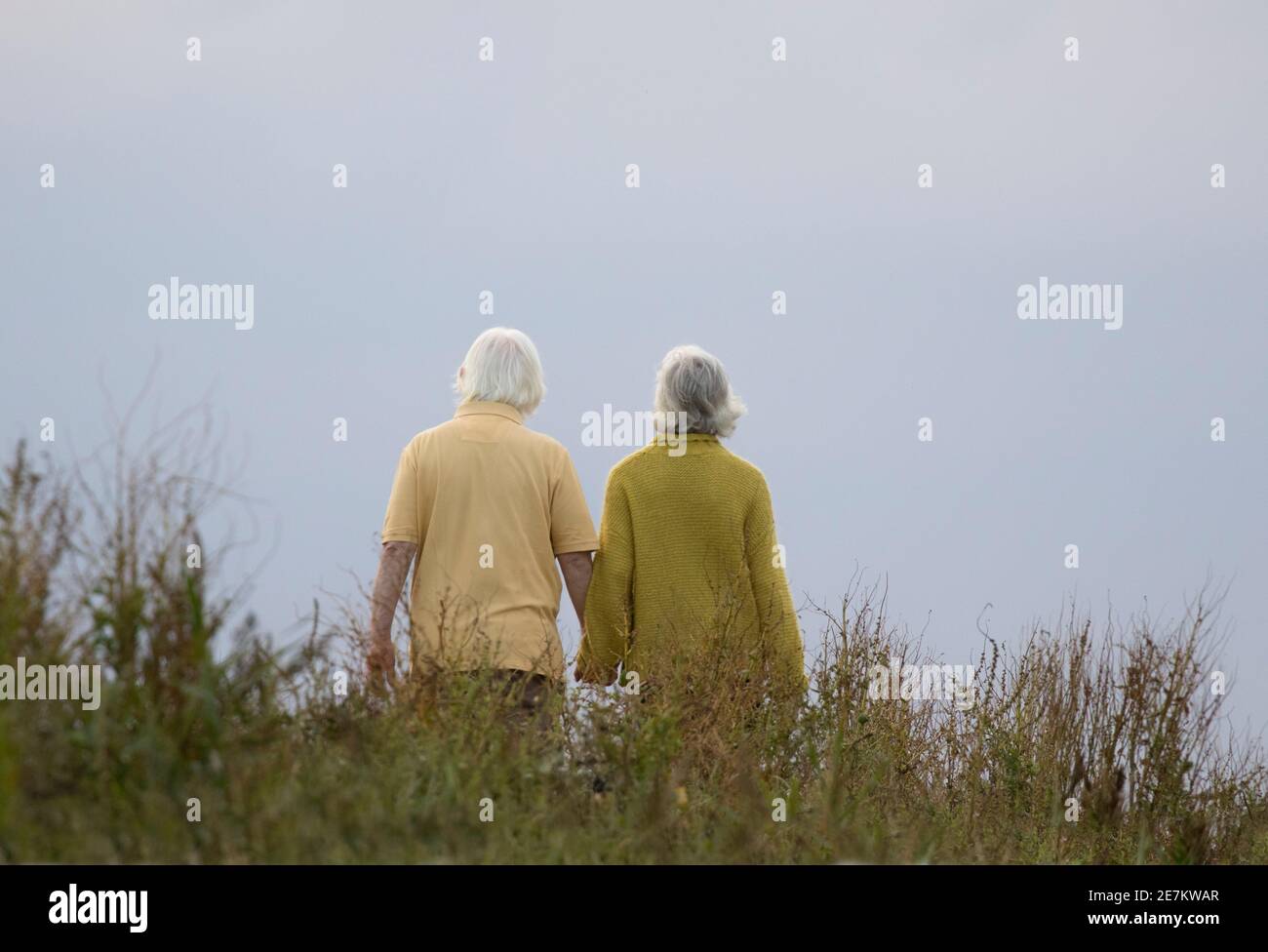 Ein älteres Paar geht Hand in Hand an einem bewölkten Tag, Norfolk, Großbritannien Stockfoto