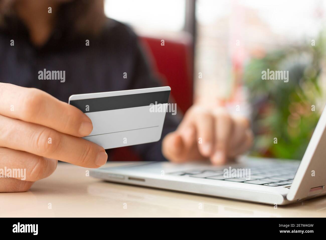 Nahaufnahme der Hände mit einer Plastikkarte. Eingabe der Kartennummer auf der Laptop-Tastatur. Online-Bezahlkonzept. Stockfoto