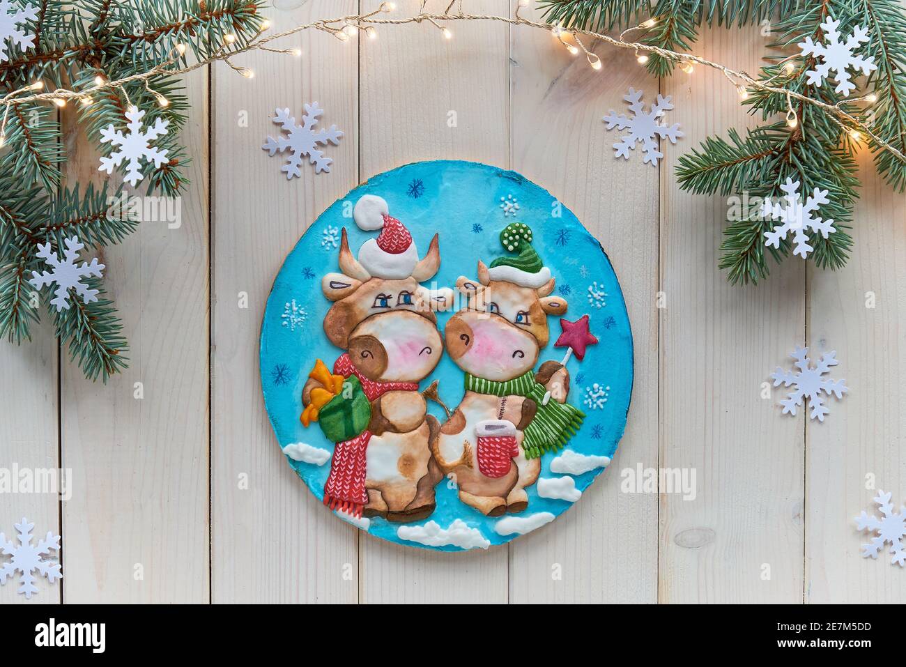 Dekoriert Lebkuchen mit zwei Comic-Kuh-Figuren. Weihnachten flach legen mit Tannenzweigen und Schneeflocken. Aus weißen Holzplanken, Draufsicht auf rustikal Stockfoto