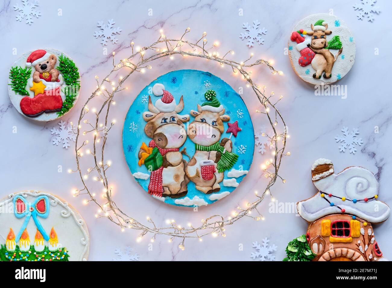 Dekoriert Lebkuchen mit zwei Comic-Kuh-Figuren, Winterhaus, Weihnachtsmann und Weihnachtskranz. Weihnachten flach lag mit festlichen Girlande eingewickelt als Stockfoto