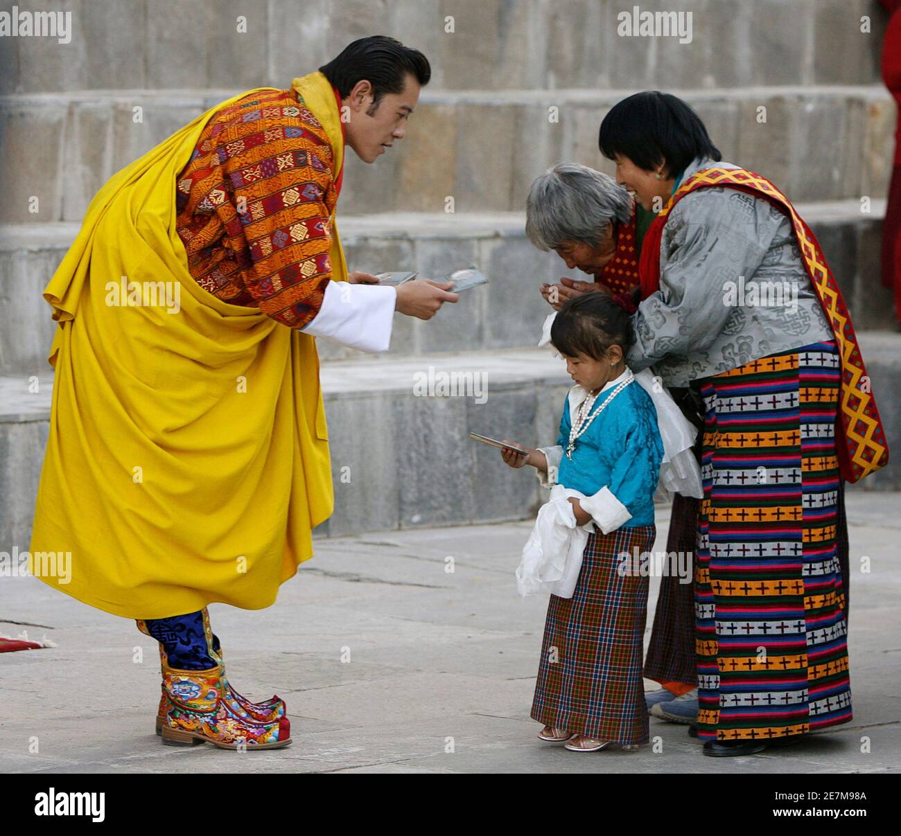 Bhutans König Jigme Khesar Namgyel Wangchuck bietet Geschenke für Menschen im Hof des Tashichhodzong Palastes während Feierlichkeiten seiner Krönungszeremonie in Thimphu 6. November 2008. Mit mittelalterlichen Tradition und buddhistische Spiritualität übernahm ein 28-jährige mit einer Ausbildung in Oxford Raven Crown of Bhutan am Donnerstag, um jüngste Demokratie der Welt zu führen, wie es in der modernen Welt entsteht. REUTERS/Desmond Boylan (BHUTAN) Stockfoto