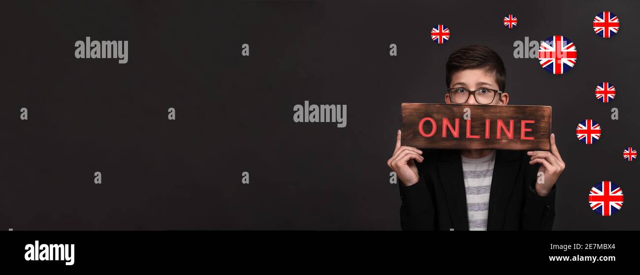 Online-Englischkurse. Bannerwerbung. Ein Teenager hält ein Holzschild mit der Inschrift online, um die Flaggen Englands. Stockfoto