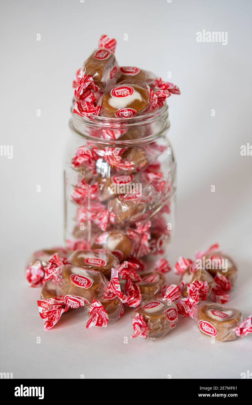 Ein Glas Ball Einmachglas überfließt mit Goetzes Unterschrift Süßigkeiten, Caramel Cremes (auch bekannt als Bull's Eyes), ein weiches Kaukaramell mit Sahne Füllung in Stockfoto
