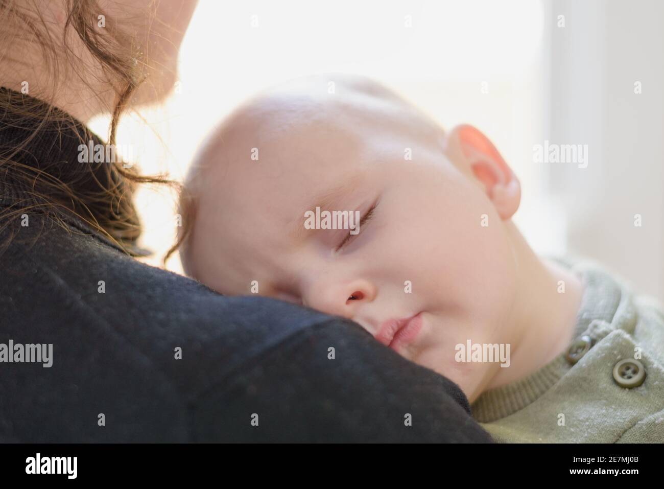 Schlafender kleiner Junge auf der Schulter der Mutter Stockfoto