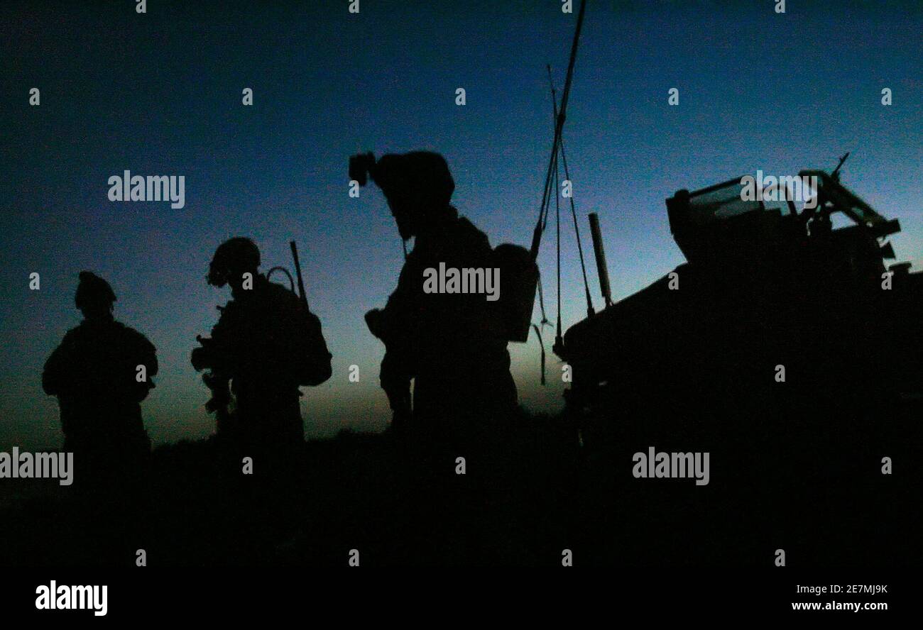 Soldaten der US-Armee stehen vor Sonnenaufgang in der Nähe ihres Fahrzeugs, während sie sich auf eine gemeinsame Operation mit irakischen Soldaten in der Nähe von Mahmudiya, südlich von Bagdad, vorbereiten 16. April 2007. REUTERS/Bob Strong (IRAK) Stockfoto