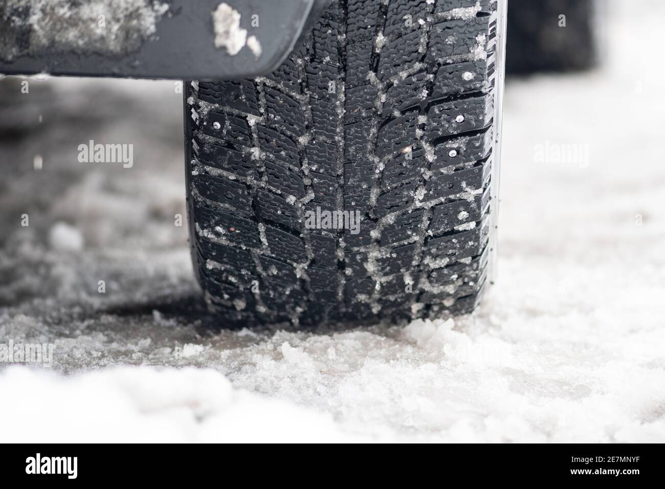 Nahaufnahme Winter übersäten Reifen eines Autos auf der Die Straße ist von Schnee und Eis bedeckt und fährt bei extremer Kälte Temperatur Stockfoto