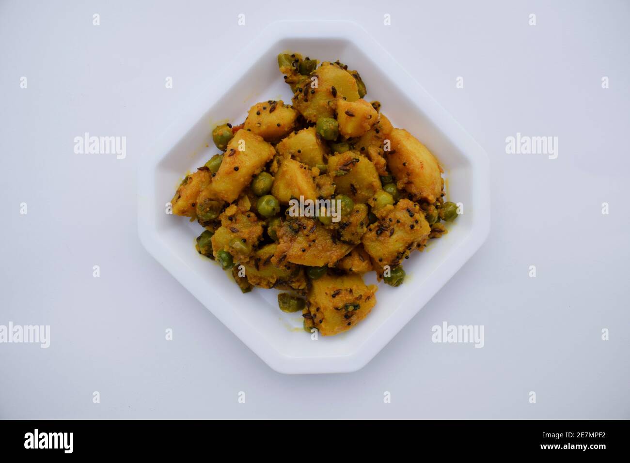 Selektiver Fokus der indischen Beilage Curry Aloo mattar KI Sabzi, beliebtes Curry aus Kartoffeln und grünen Erbsen auf weißem Hintergrund Stockfoto