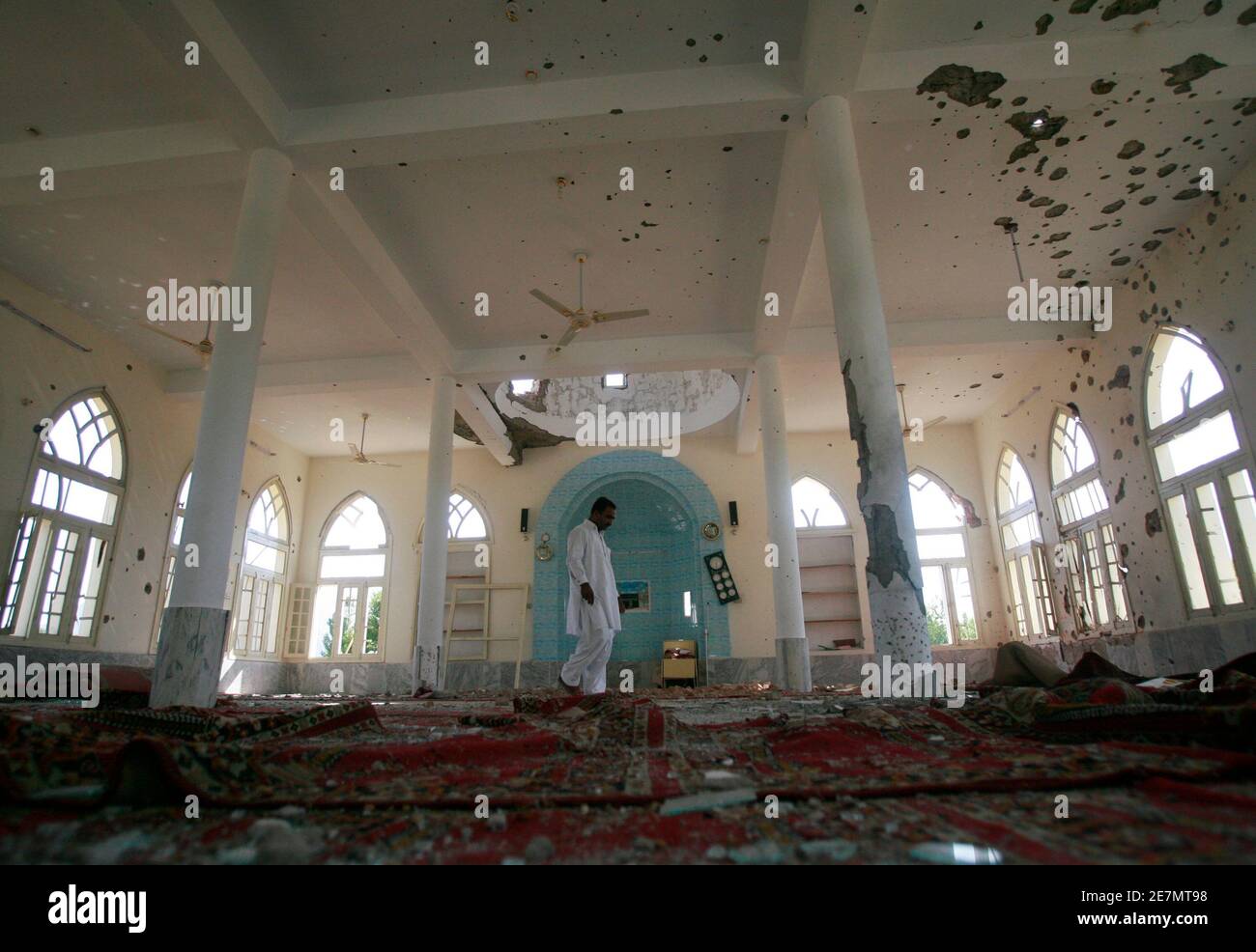 Ein Mann geht durch einen beschädigten Moschee während einer temporären Leichtigkeit in Ausgangssperre in Buner Bezirk, etwa 190 km (118 Meilen) nordwestlich von der pakistanischen Hauptstadt Islamabad, 28. Mai 2009. Zwei Bomben explodierten in einem Markt in der nordwestlichen pakistanischen Peshawar am Donnerstag, sechs Menschen getötet und bewaffneten auf Dächern überfallen Polizei, da sie am Tatort eintraf.   REUTERS/Faisal Mahmood (PAKISTAN-Politik-Konflikt) Stockfoto