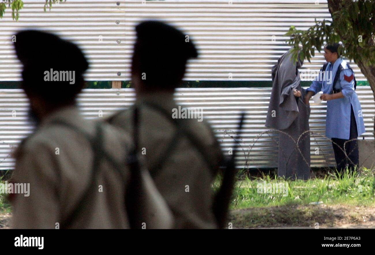 Eine pakistanische Polizistin (R) frisks ein nicht identifizierter Burka bekleidet radikale religiöse Student (2. R) nach ihrer Kapitulation in der Nähe von Lal Masjid oder die rote Moschee in Islamabad 6. Juli 2007. Schwere Austausch von Feuer brach am Freitag zwischen militante Islamisten in eine pakistanische Moschee und Sicherheitskräfte verschanzt, nachdem ihr Anführer sagte, dass er und seine Hunderte von Anhängern würde lieber sterben, als sich zu ergeben.   REUTERS/Faisal Mahmood (PAKISTAN) Stockfoto