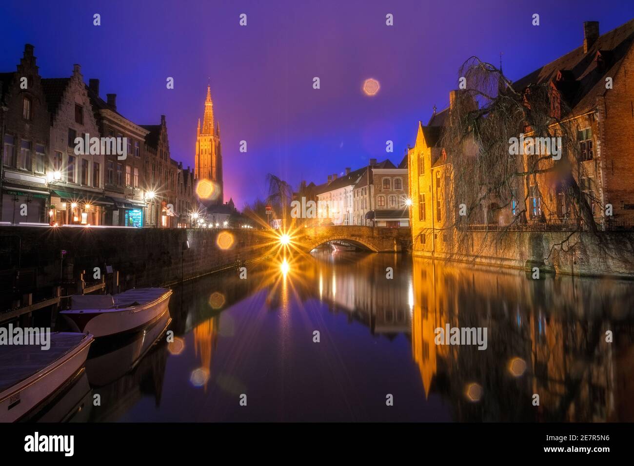 Ikonische märchenhafte Ansicht der Kanäle von Brügge, während des Regens. Nepomucenusbrücke und Kirche unserer Lieben Frau Brügge im Hintergrund. Belgien Stockfoto