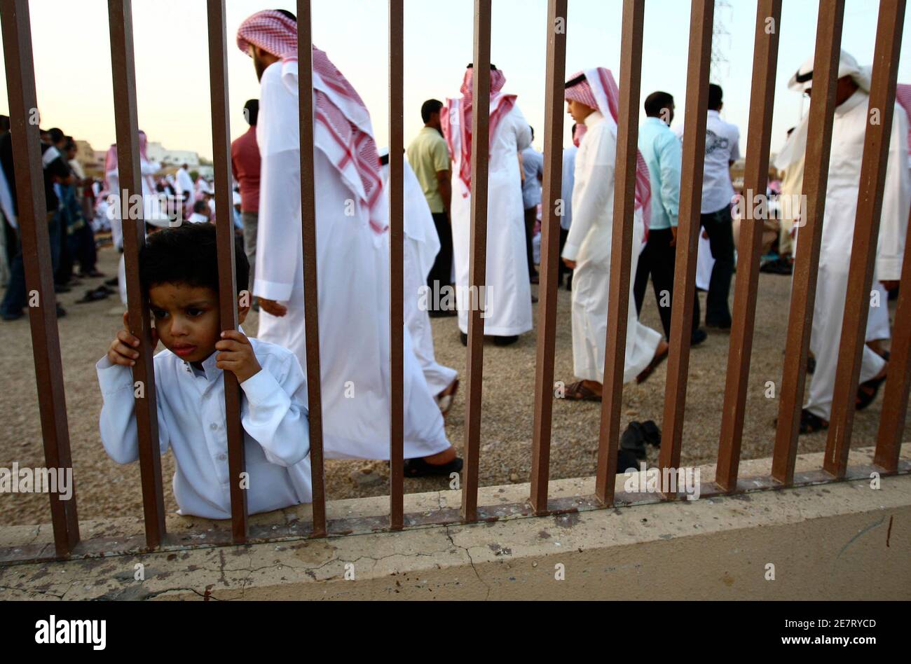 Ein Junge schaut zu, wie Menschen Gebete markiert das Ende des Fastenmonats Ramadan in zentralen Riad 20. September 2009 teilnehmen. Eid al-Fitr kennzeichnet das Ende des Ramadan, der heiligste Monat im islamischen Kalender, während, den Muslime auf der ganzen Welt aus Essen, trinken und Geschlechtsverkehr von Sonnenaufgang bis Sonnenuntergang verzichten.   REUTERS/Fahad Shadeed (Saudi-Arabien-RELIGION-Gesellschaft) Stockfoto
