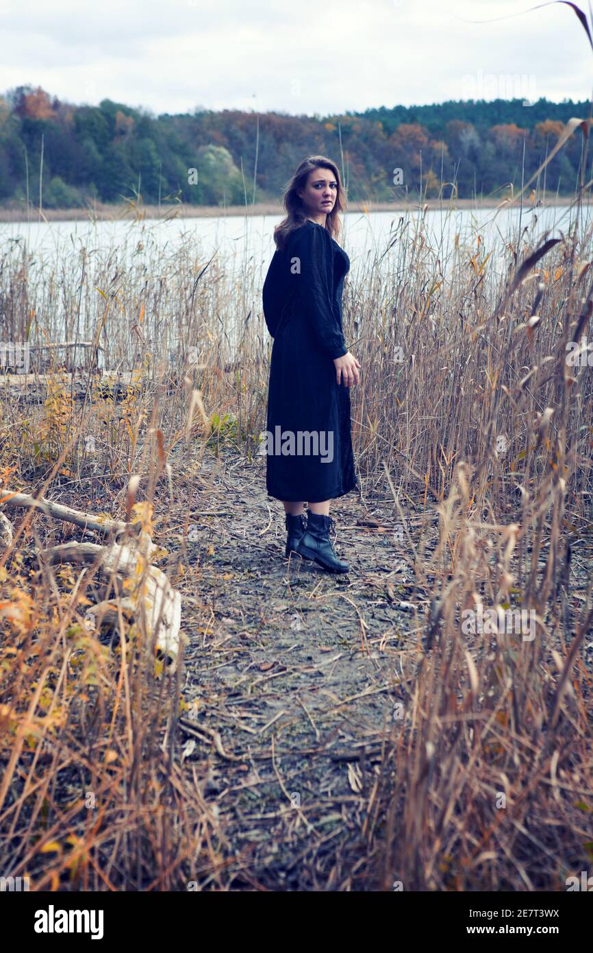 Brunette Frau in schwarzem Kleid ein See suchen erschrocken Stockfoto