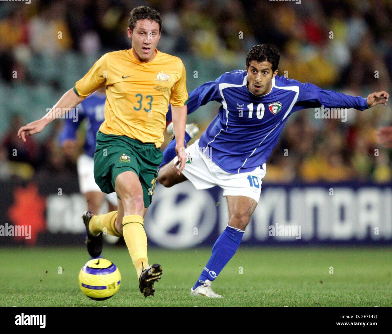 Der Australier Mark Milligan (L) sieht zu, wie der Kuwaitische Khalaf Al Mutairi beim Asian Cup Qualifying Match in Sydney am 16. August 2006 den Ball an ihm vorbeischießt. REUTERS/will Burgess (AUSTRALIEN) Stockfoto