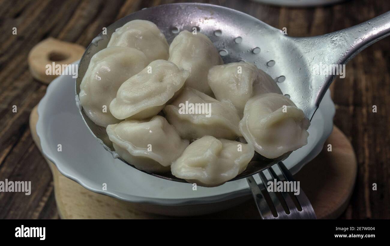 Appetitlich gekochte Knödel, Gießen Knödel in einen Teller aus einer Metalllöffel. Stockfoto