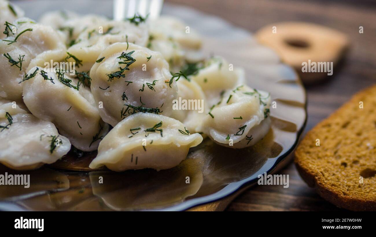 Hausgemachte Knödel in einem Teller auf einem Holztablett, Knödel auf einer Gabel, leckeres Essen. Stockfoto
