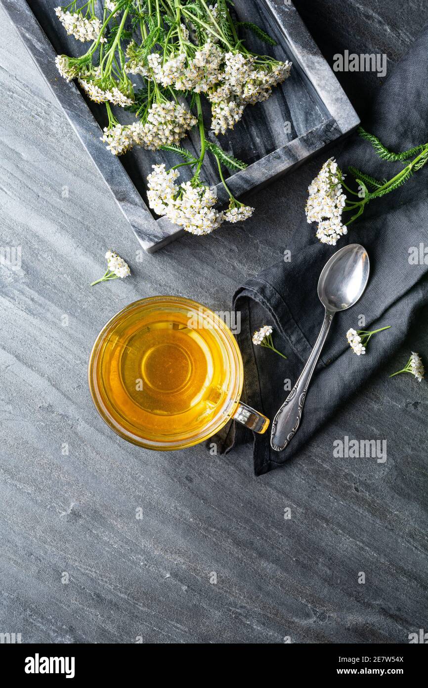 Heilkräuter Tee aus Schafgarbe, Heilmittel zur Wundheilung auf rustikalem Steingrund mit Kopierraum Stockfoto