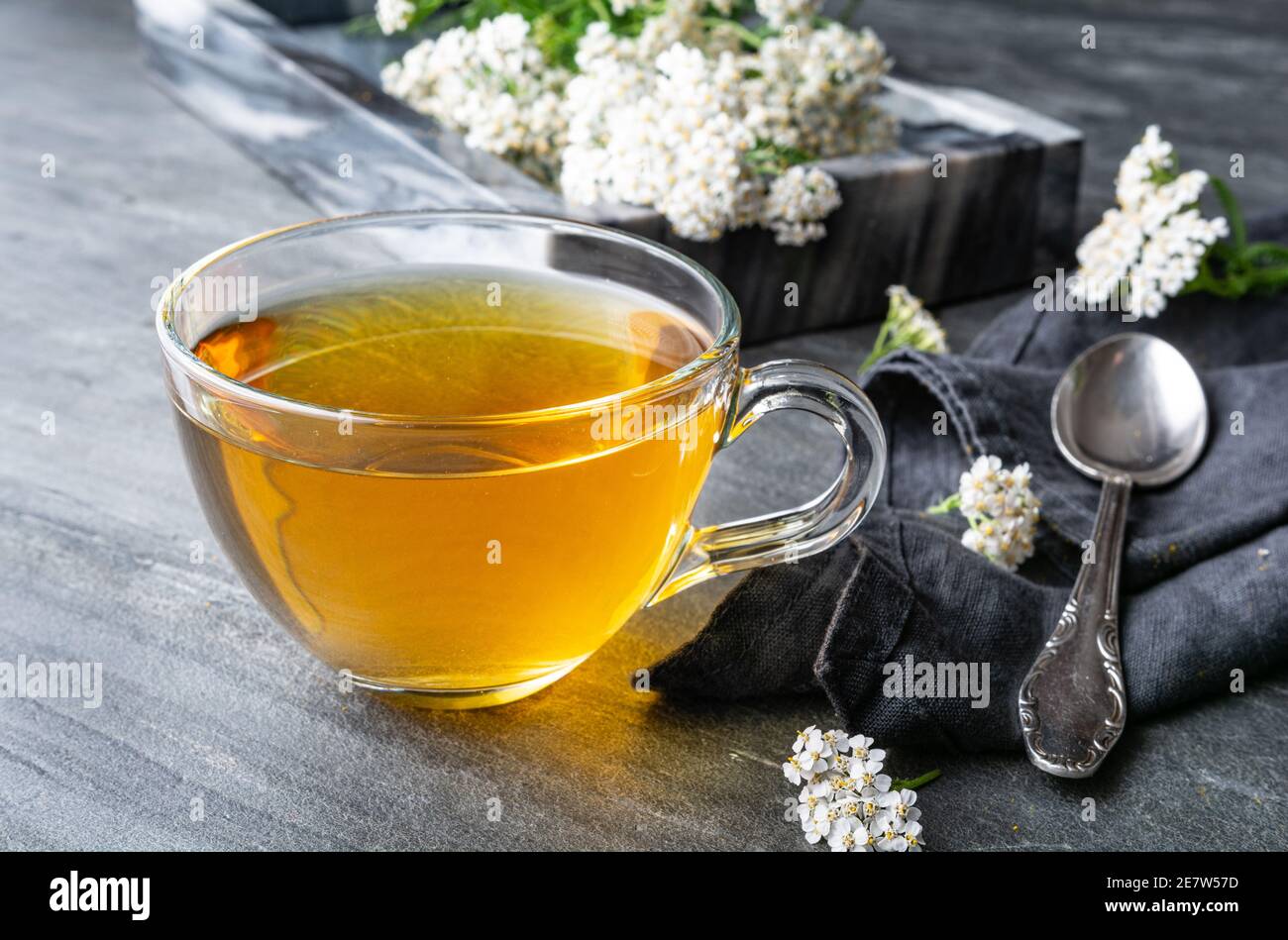 Heilkräuter Tee aus Schafgarbe, Heilmittel zur Wundheilung auf rustikalem Steingrund Stockfoto