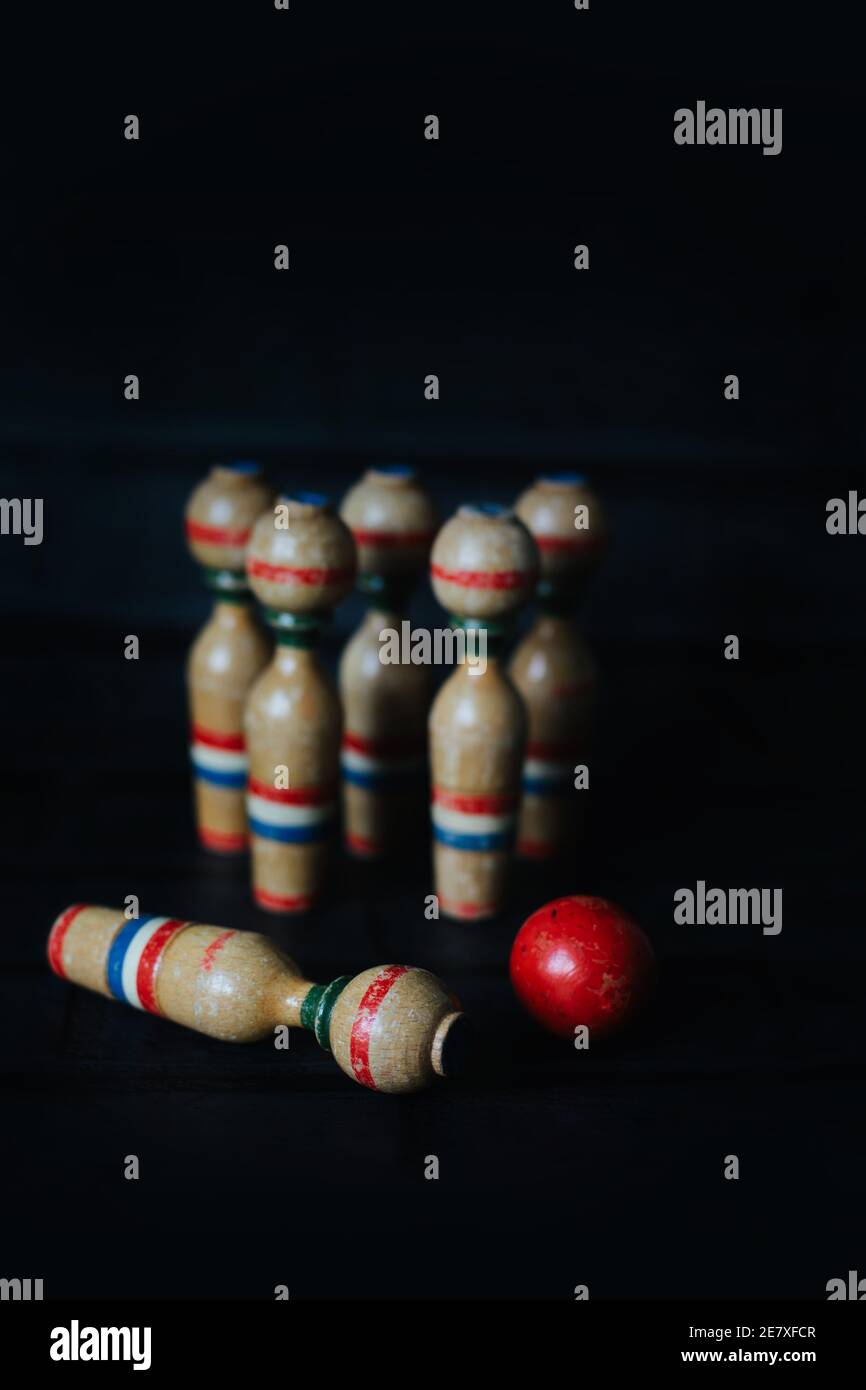 Eine Gruppe von alten hölzernen Bowling Kegeln und rote Kugel Mit einem umgeklopft Stockfoto