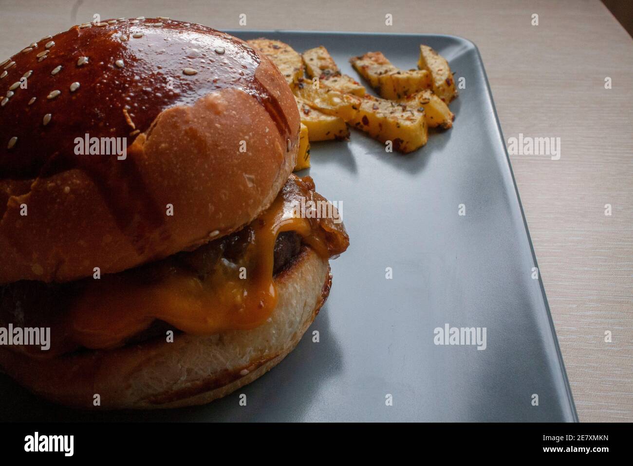 Hausgemachter Hamburger mit gebackenen Kartoffeln, gegrilltes Rindfleisch. Einige Bereiche sind außer Fokus. Selektiver Fokus auf Hamburger Stockfoto