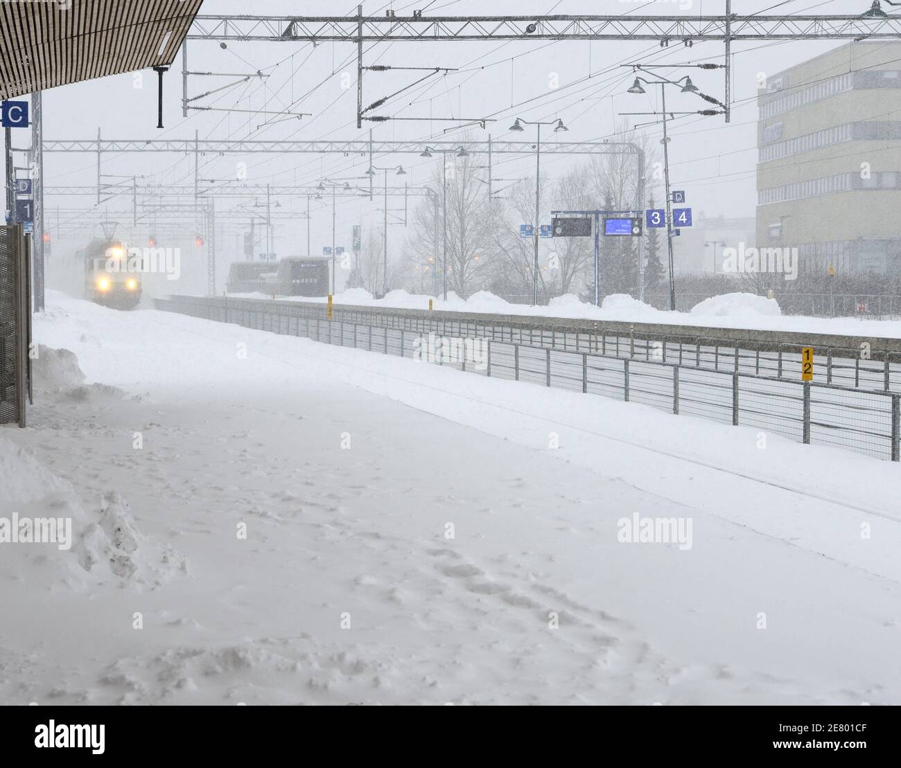 Der Zug kommt während eines Schneesturms am Bahnhof an Stockfoto