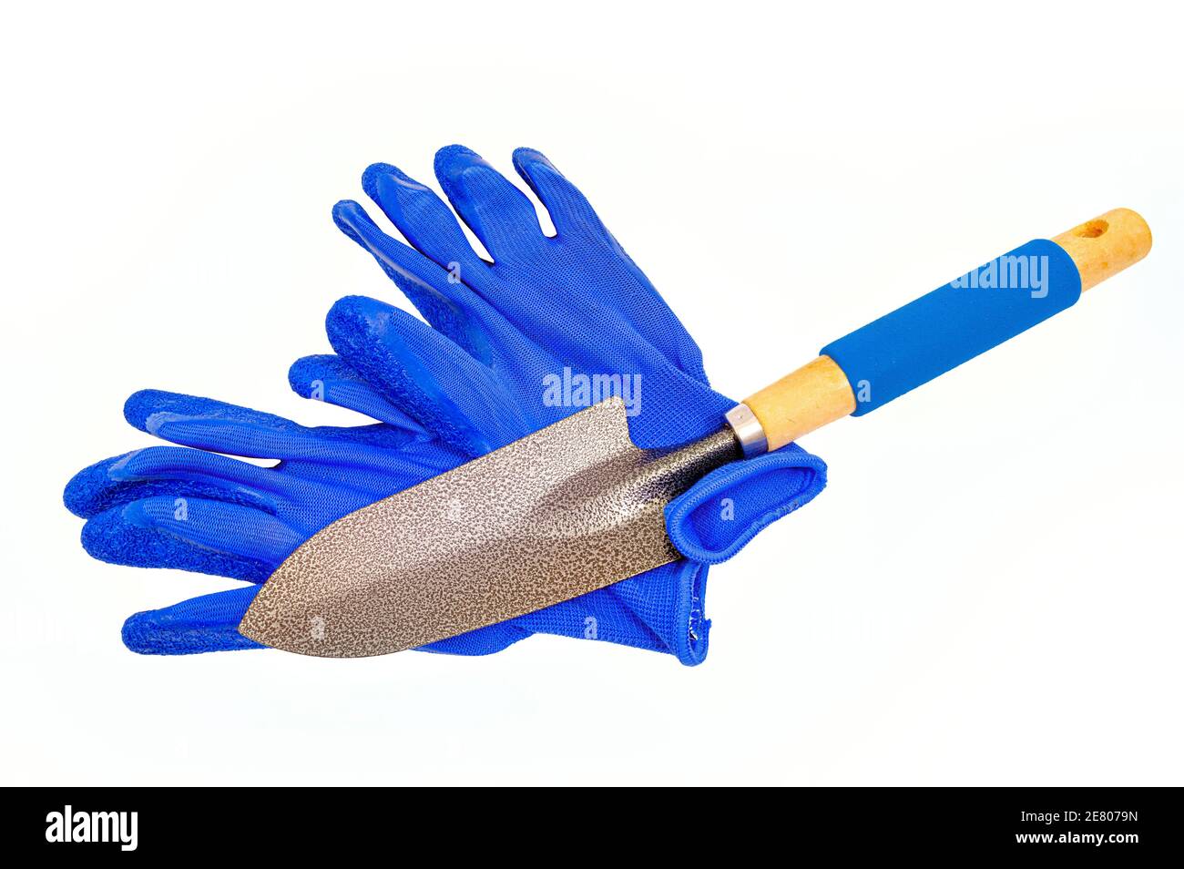 Horizontale Aufnahme von blauen Gartenhandschuhen mit einer Kelle über sie isoliert auf weiß gelegt. Stockfoto