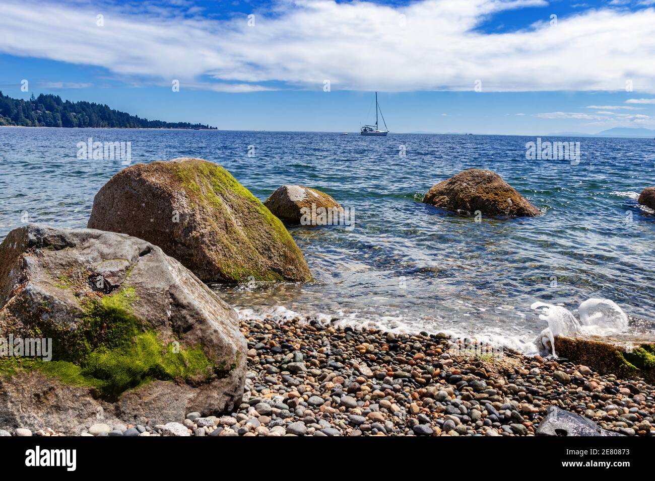 Entferntes Segelboot in der Nähe von Sechelt Beach, Sunshine Coast, BC, Kanada. Sechelt ist eine der großen Städte an der Sonnenküste von BC, Kanada. Ein wunderschöner Strand Stockfoto