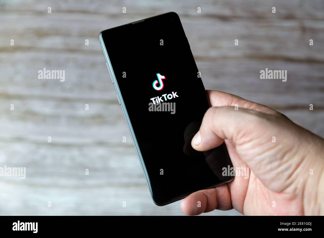 Eine Hand, die ein Mobiltelefon oder Mobiltelefon mit hält Die TikTok Social Media App wird auf dem Bildschirm geöffnet Stockfoto