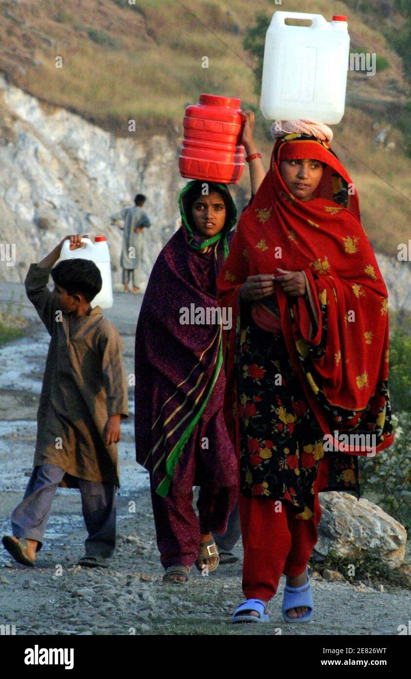 Überlebenden des Erdbebens 8. Oktober 2005 tragen Gießkannen, wie sie ein Refugium-Lager in der verwüsteten Stadt Muzaffarabad, die Hauptstadt von Pakistan verwalteten Kaschmir 6. Oktober 2006 zurück. Pakistans Präsident Pervez Musharraf aufgefordert die internationale Hilfe-Gemeinschaft am Donnerstag für eine zusätzliche $ 800 Millionen Kosten für den Wiederaufbau nach einem verheerenden Erdbeben vor einem Jahr zu decken.   REUTERS/Faisal Mahmood (PAKISTAN verwalteten Kaschmir) Stockfoto