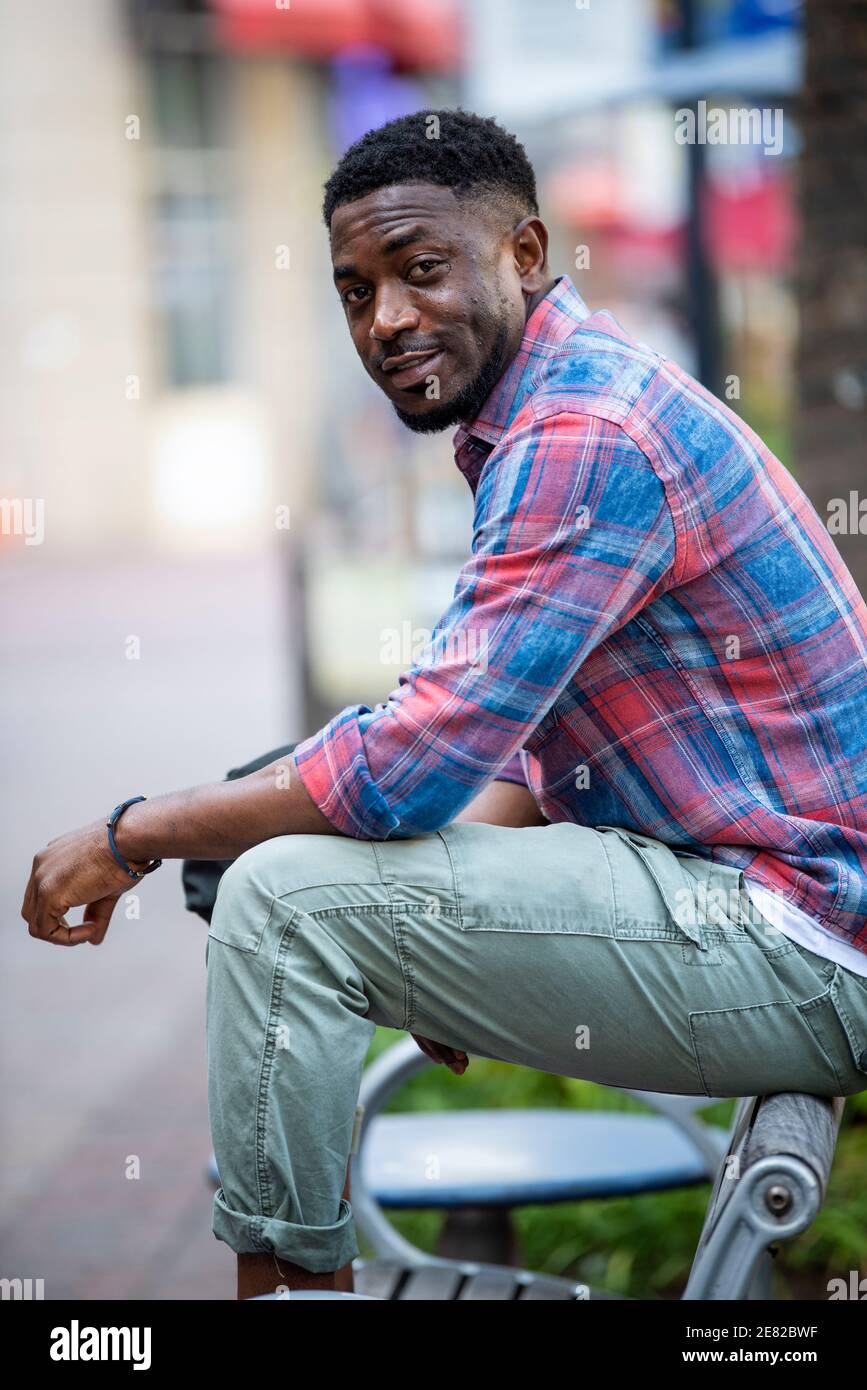 Ein schwarzer Mann sitzt auf einer Straßenbank urbane Einstellung. Stockfoto