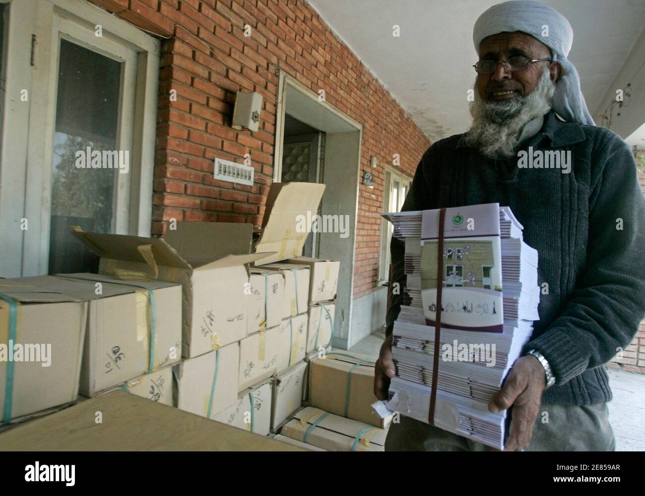 Ghulam Rafiq, Hausmeister einer Wahlkommission Amt trägt Kopien der Wahl Handbücher in Attock ungefähr 100 Kilometer (62 Meilen) nordwestlich von Islamabad, 24. Dezember 2007. Die pakistanische Wahlkommission Büro in der Stadt Attock befindet sich in einem heruntergekommenen Gebäude am Rande der Stadt.     REUTERS/Faisal Mahmood (PAKISTAN) Stockfoto