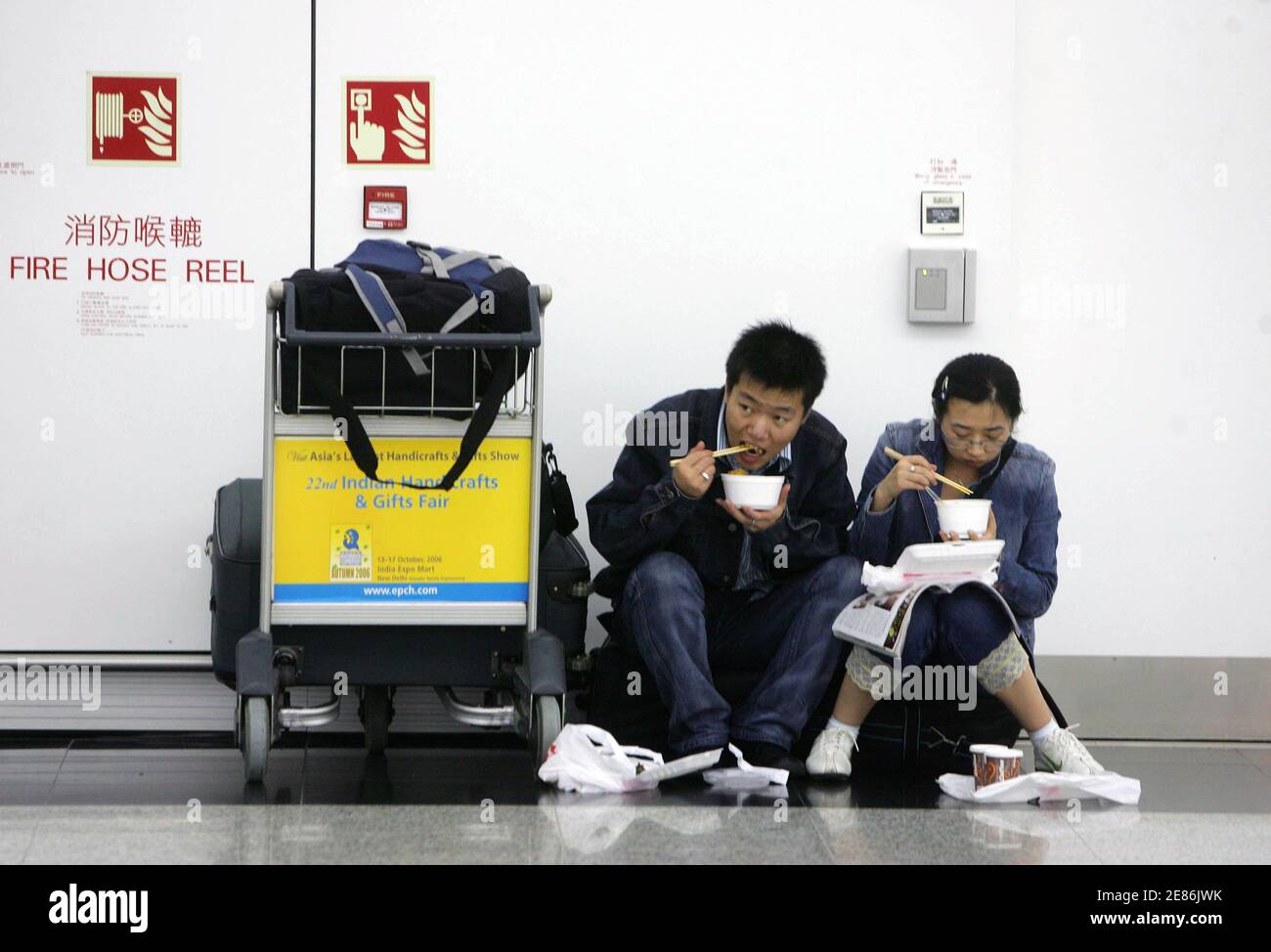 Passagiere essen Nudeln am Hong Kong International Airport 3. August 2006. Obwohl Hongkong einen Volltreffer von Prapiroon verschont werden dürfte, haben starke Winde 159 Flüge, verzögert, während 92 abgesagt wurden und 70 wurden an andere Orte nach der Airport Authority umgeleitet. Rund 3.000 Passagiere haben auf dem Flughafen, während ein weiterer 300 Flüge wahrscheinlich bis Mitternacht gestört werden geerdet.     REUTERS/Paul Yeung (HONG KONG) Stockfoto