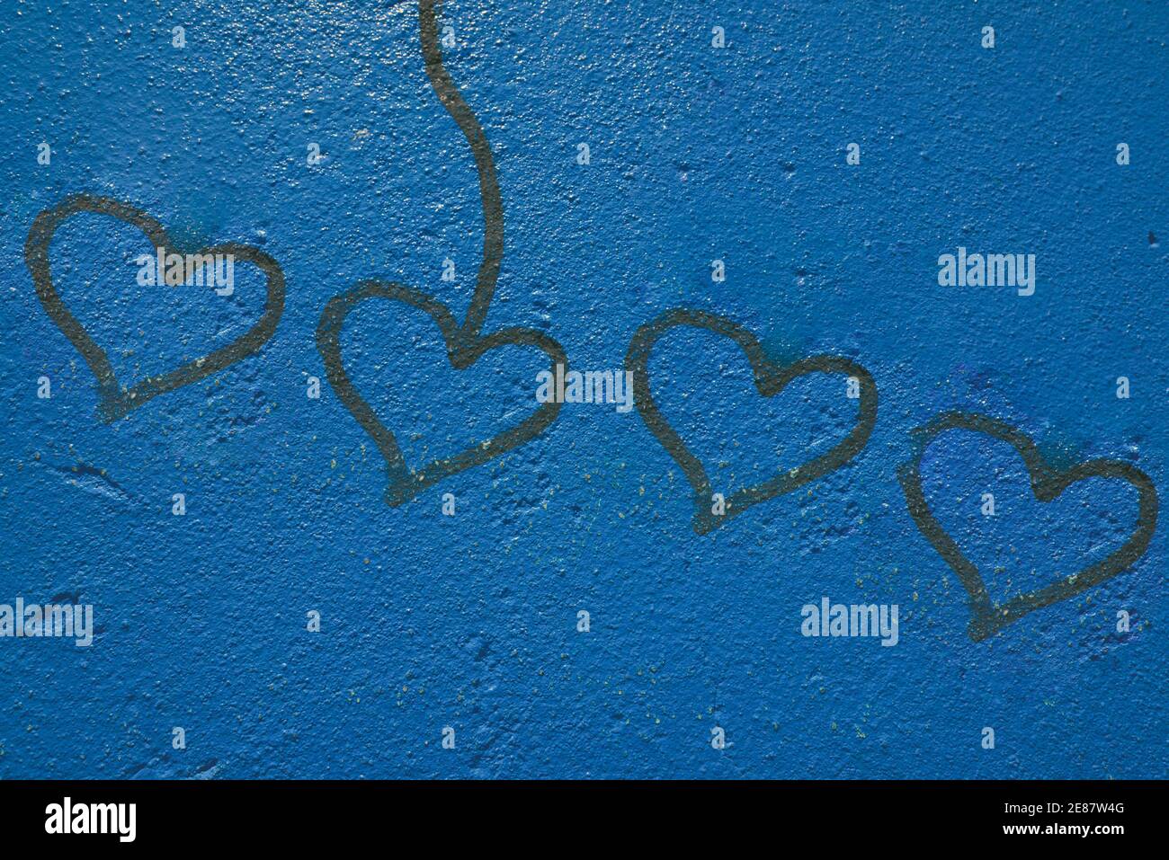 Blau bemalte Wand mit vier aufeinander abgestimmten Herzzeichen Störung mit einem Herzen verbunden mit Linie Stockfoto