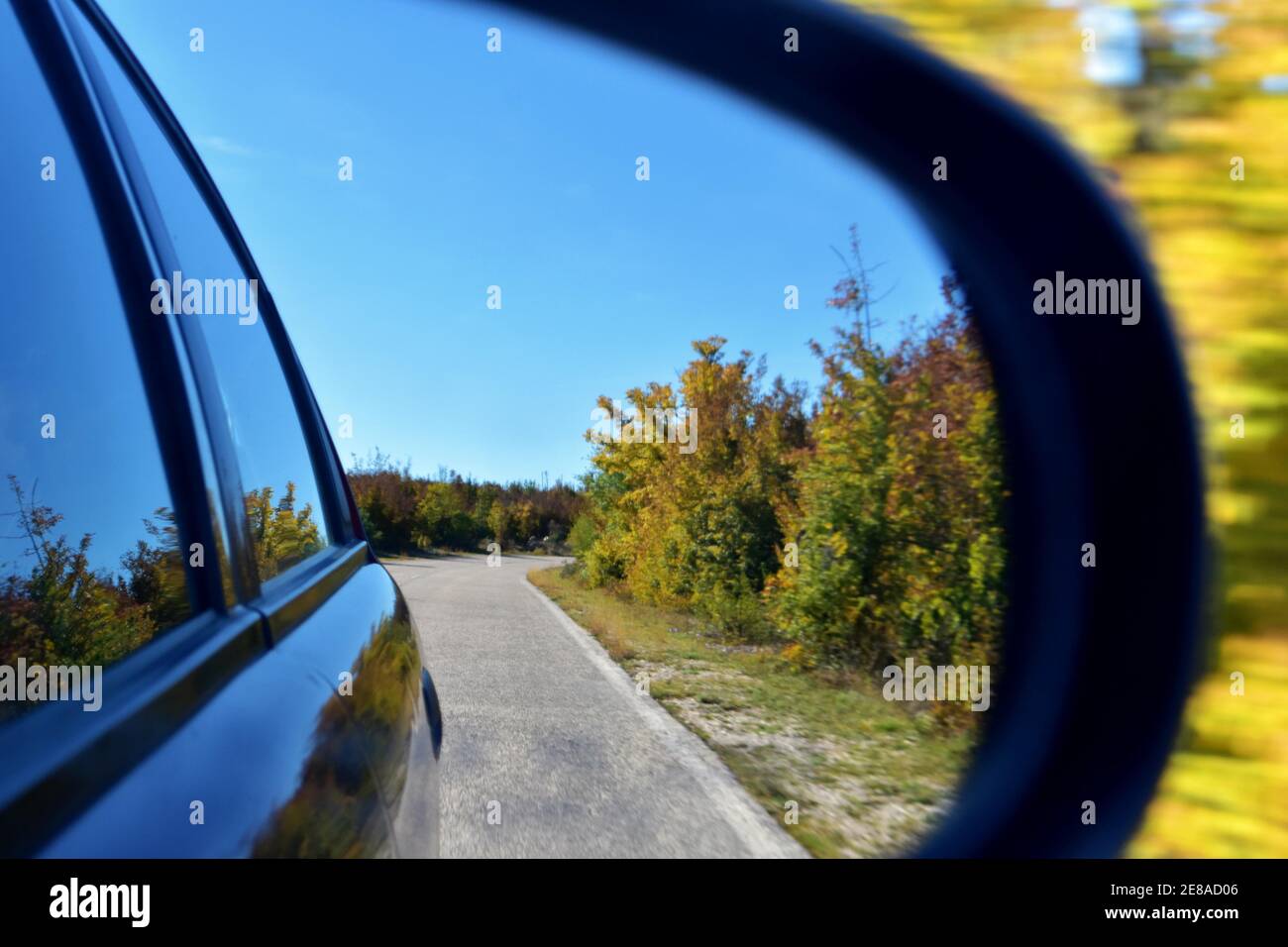 Blick auf den Außenspiegel des Autos, der Spiegel reflektiert Straße, Natur  mit grünen Hügeln und einem blauen Himmel mit Wolken Stockfotografie - Alamy
