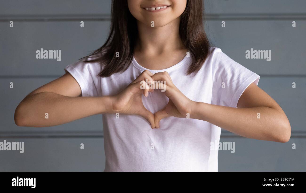 Close up lächelnd liebenswert kleines Mädchen zeigt Herz Geste Stockfoto