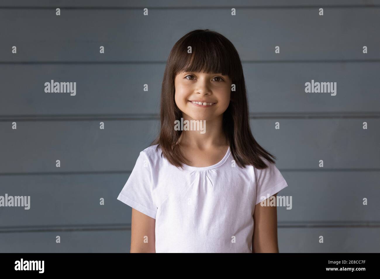 Kopf erschossen Porträt lächelnd kleines Mädchen auf grauen Studio-Hintergrund Stockfoto