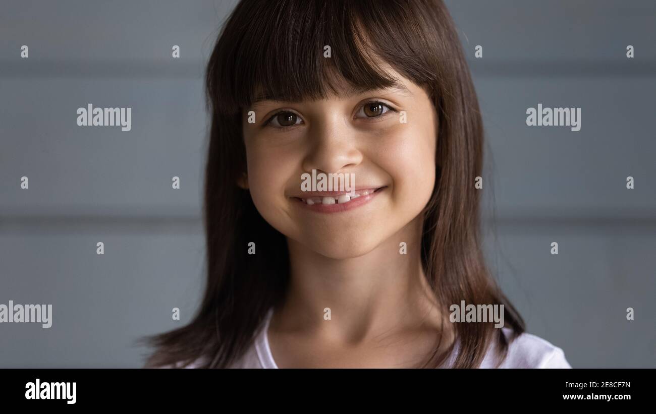 Kopf erschossen Porträt lächelnd niedlichen kleinen Mädchen auf grauem Hintergrund Stockfoto