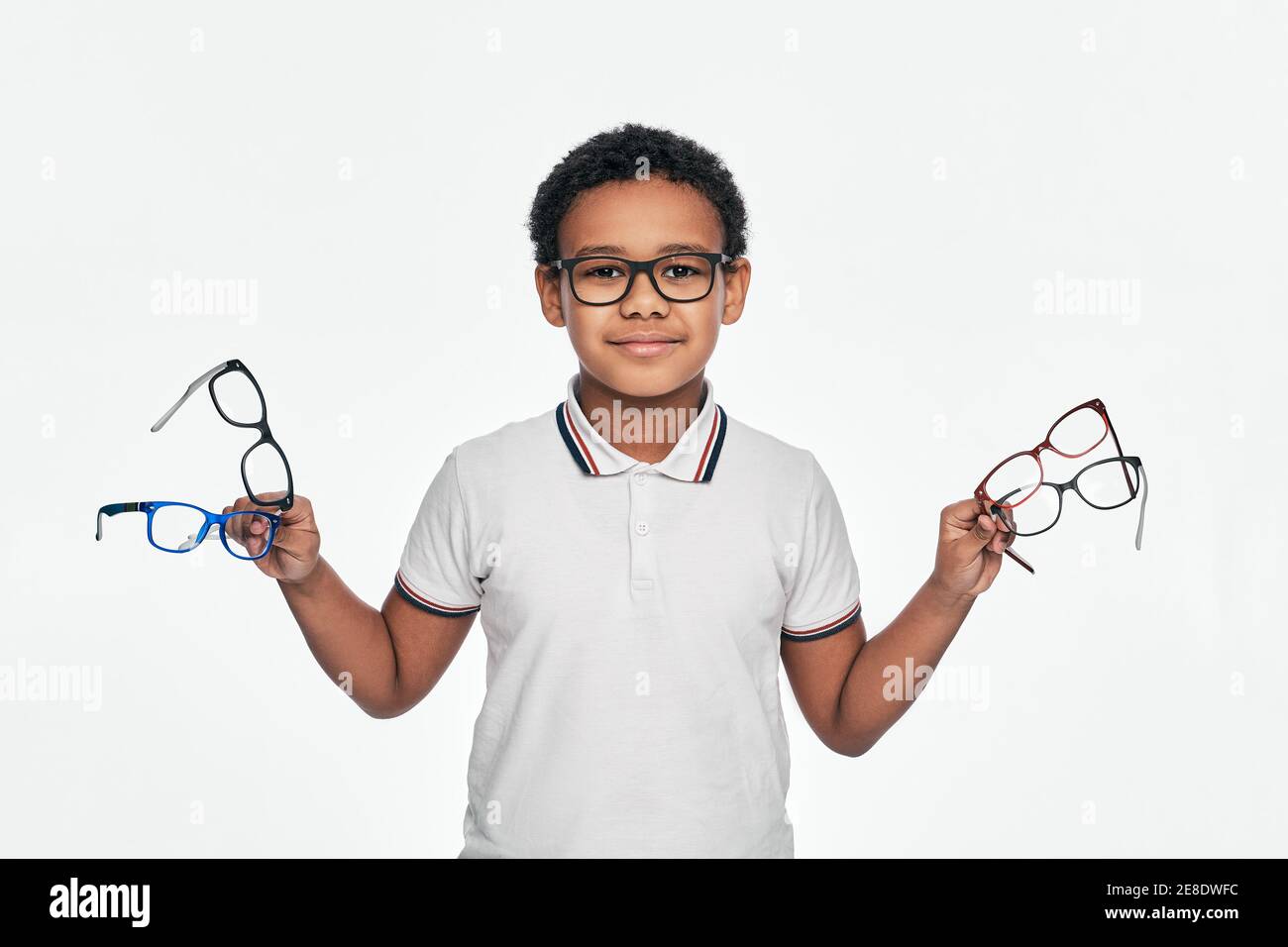 Afroamerikanischer Junge hält viele stilvolle Brillen in den Händen, für Sehkorrektur für Kinder. Isoliert auf Weiß Stockfoto