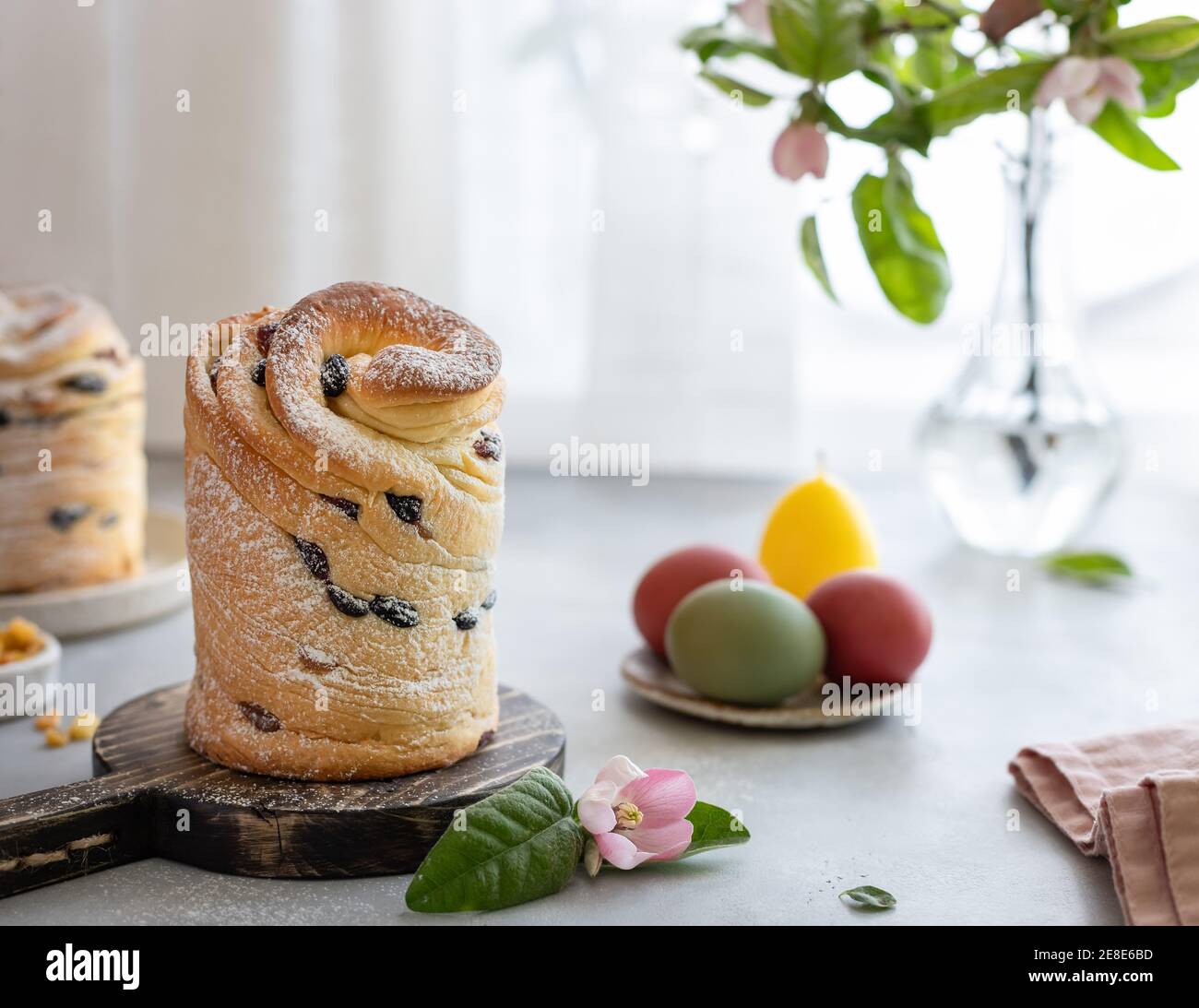 Osterkomposition mit Cruffin Kulich, bemalte Eier, blühender Apfelzweig Stockfoto