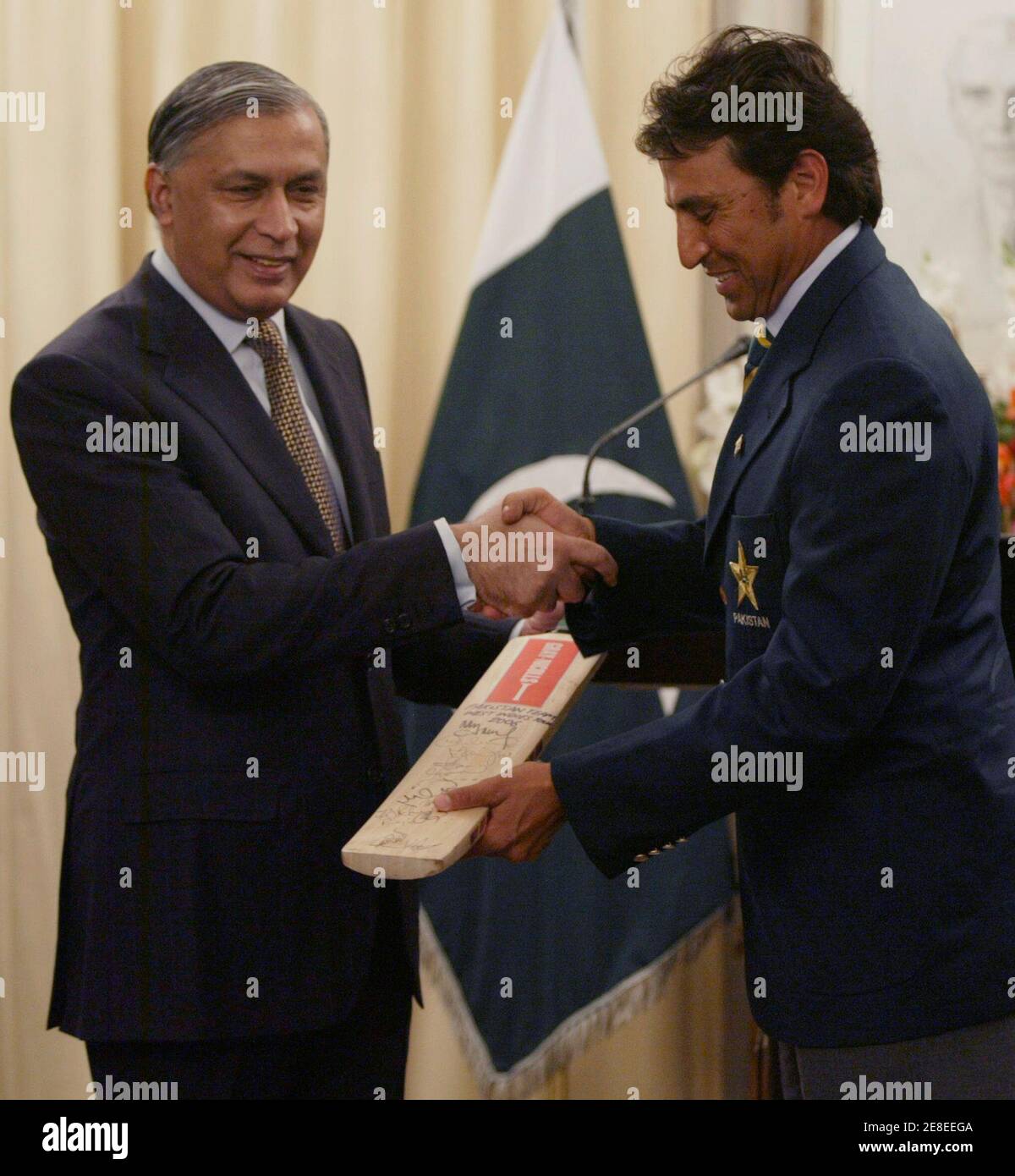 Pakistanischer Cricketspieler Younis Khan (R) verleiht eine Fledermaus mit den Unterschriften von seinen Teamkollegen Pakistans Premierminister Shaukat Aziz im Rahmen eines Empfangs im Premierminister House in Islamabad 2. Dezember 2006.  REUTERS/Faisal Mahmood (PAKISTAN) Stockfoto