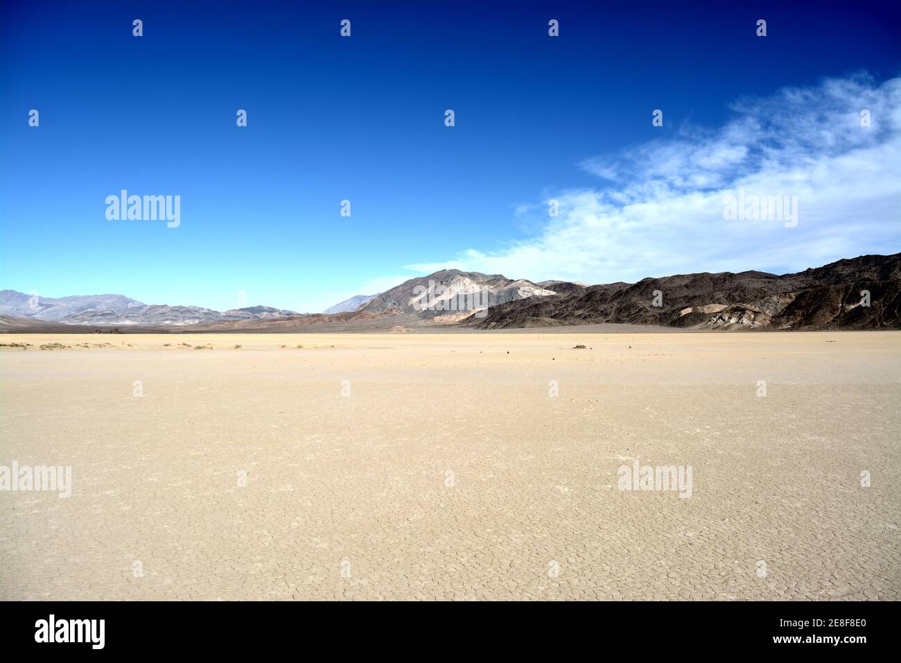 Trockene und rissige Erde mit Bergen im Hintergrund Die Rennstrecke Playa im Death Valley Nationalpark Stockfoto