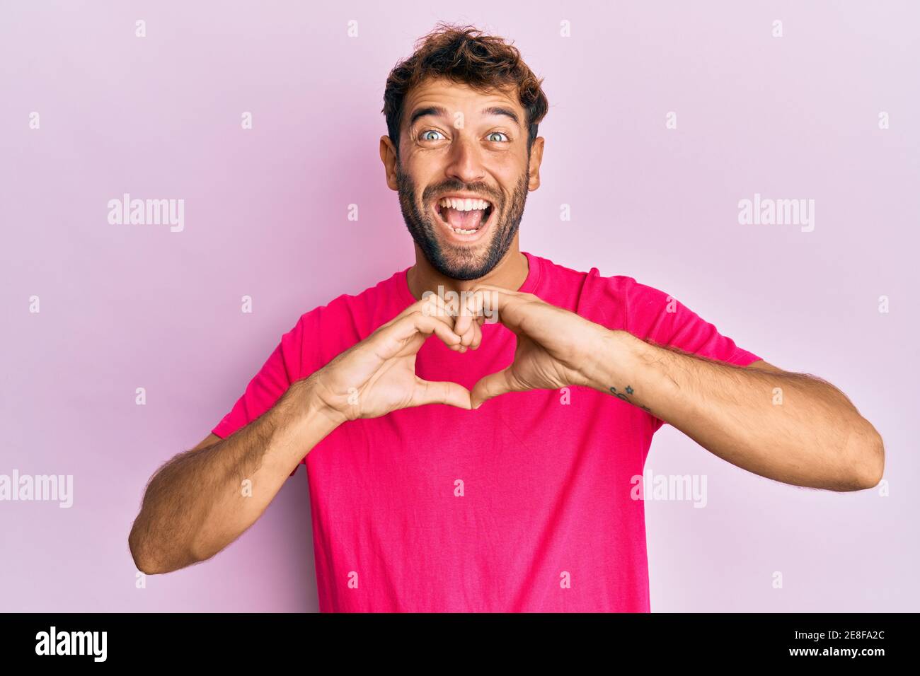 Schöner Mann mit Bart macht Herz Symbol mit Händen Form feiert verrückt und erstaunt für den Erfolg mit offenen Augen schreien aufgeregt. Stockfoto
