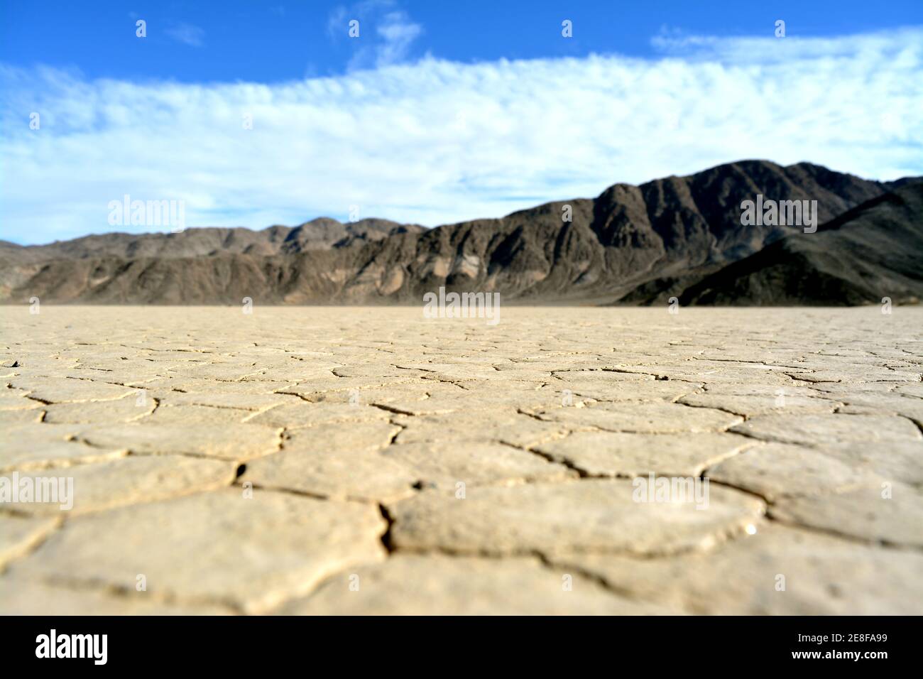 Trockene und rissige Erde mit Bergen im Hintergrund Die Rennstrecke Playa im Death Valley Nationalpark Stockfoto
